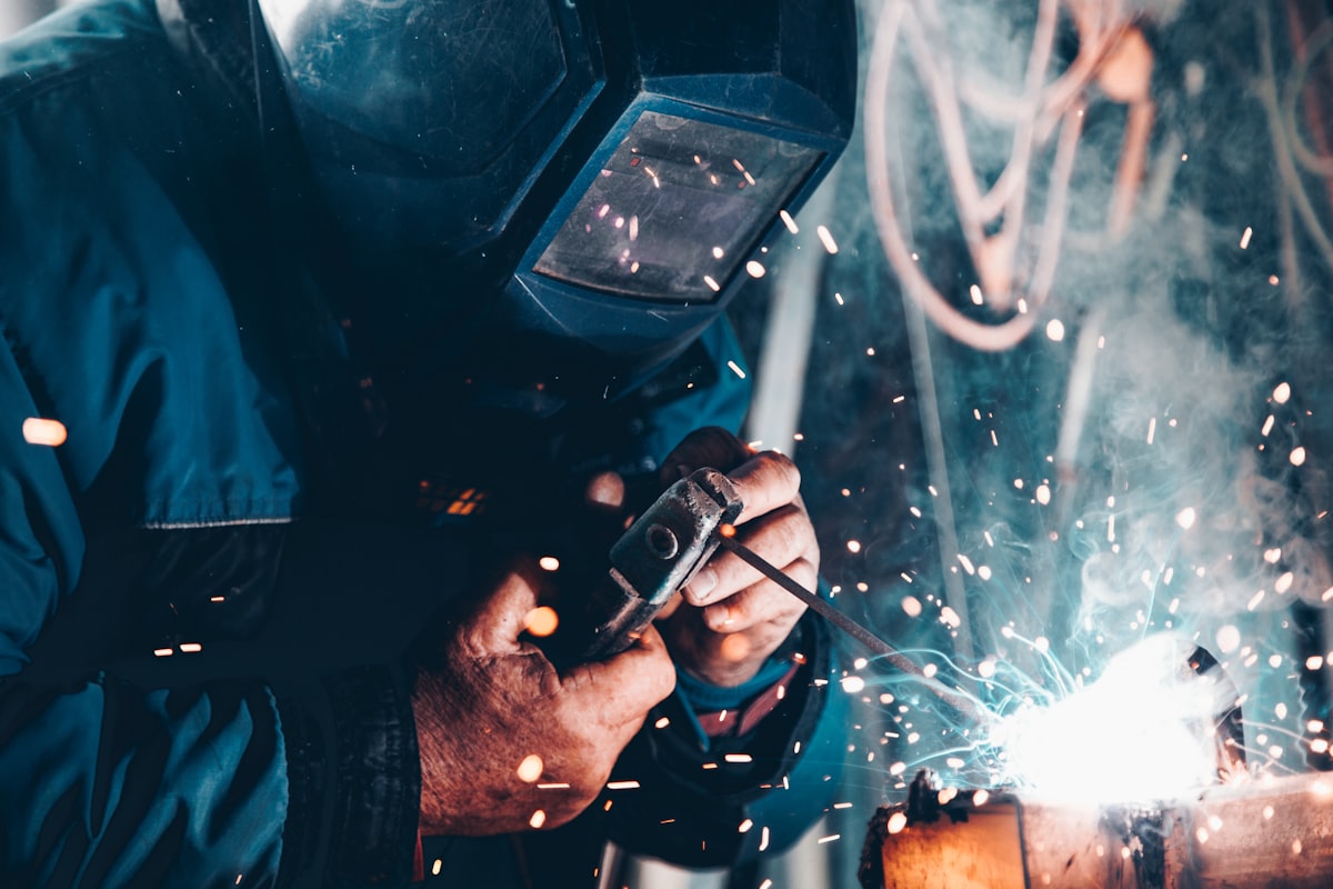 Soldador trabajando en planta de fabricación industrial, representando la ingeniería detrás de Infinity Rotomolding